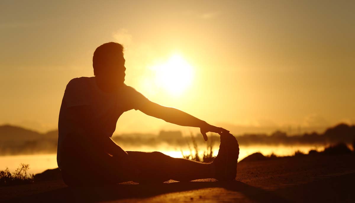 a man stretching while looking to the sun