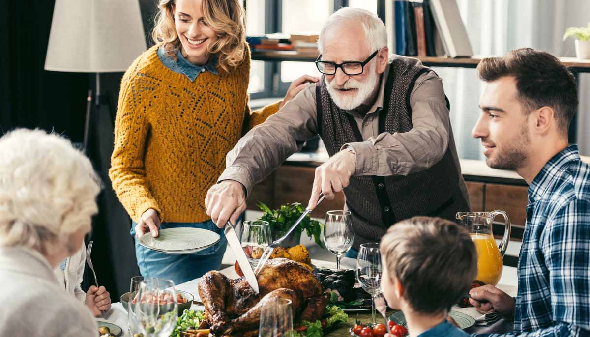 Family watches on as grandpa carves the Thanksgiving turkey