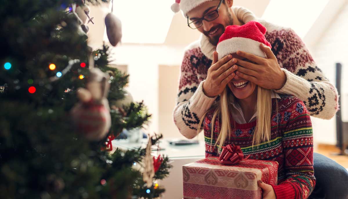 A couple excitedly opens Christmas presents