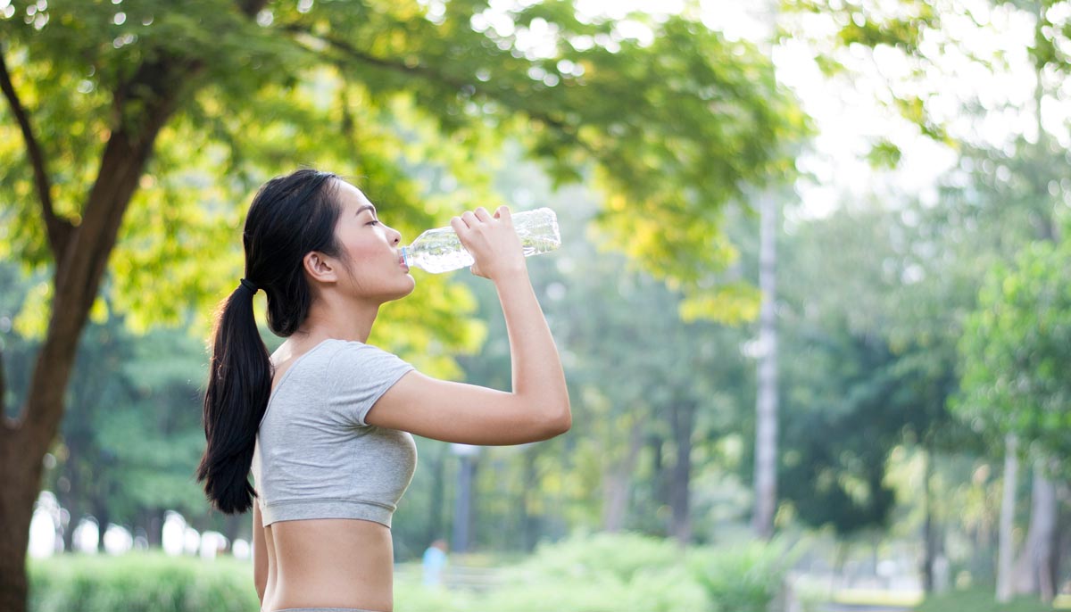 Healthy young woman out on a run, taking a swig from her water bottle
