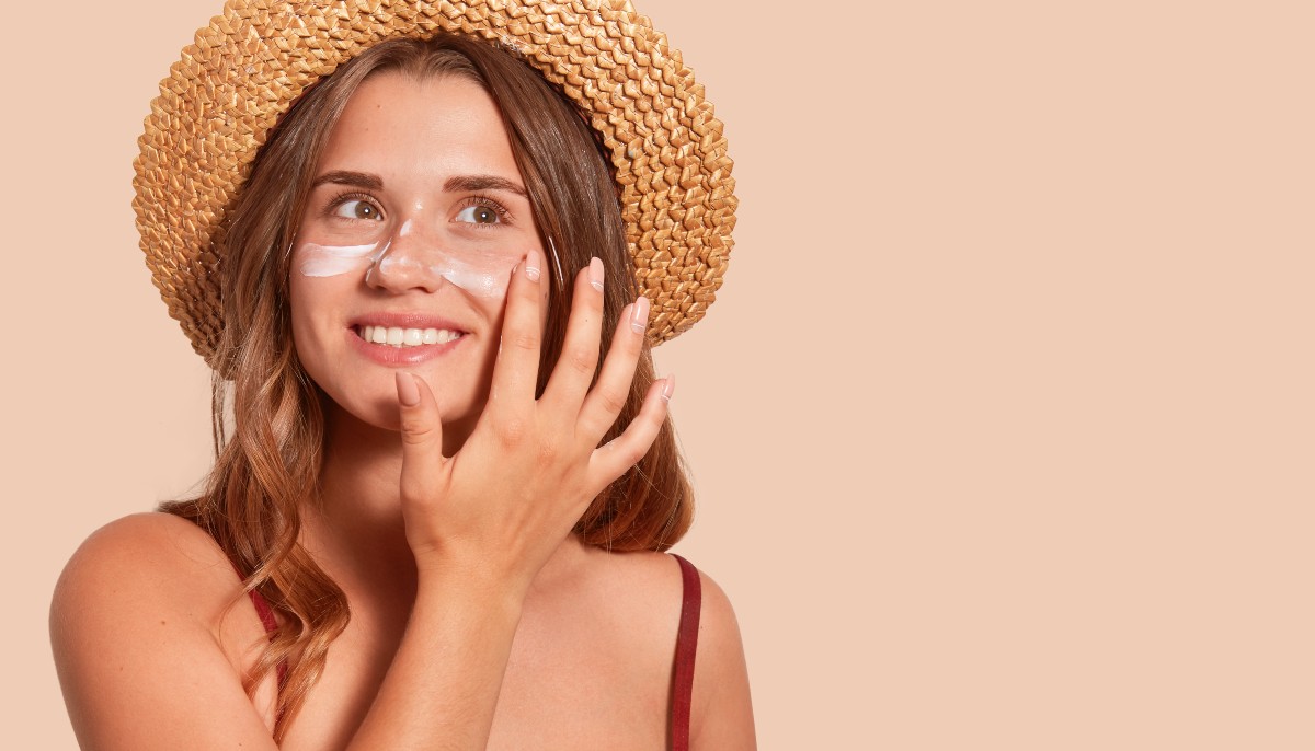 Woman in a hat applying sunscreen